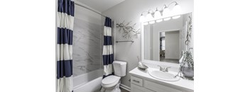 A white and navy blue bathroom with a toilet, sink, and striped shower curtain.