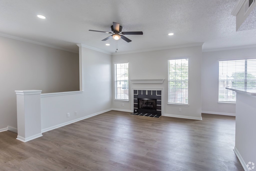 A spacious living room with a fireplace and a ceiling fan.
