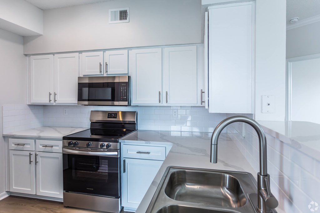A kitchen with white cabinets and a stainless steel sink.