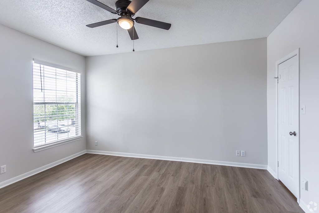 A room with a ceiling fan and a window with blinds.