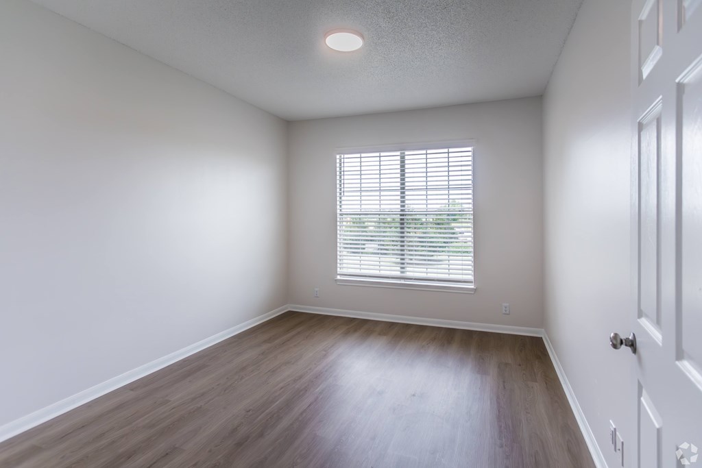 A room with a window and wooden flooring.