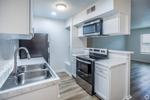 A kitchen with a stainless steel sink and a black oven.