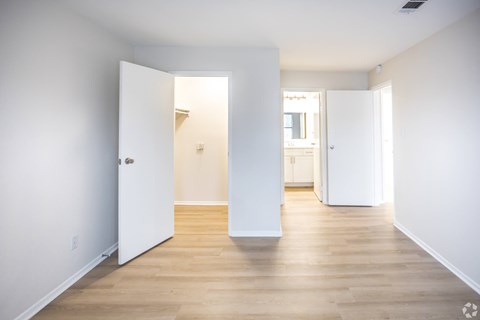 A white room with a wooden floor and two open doors.