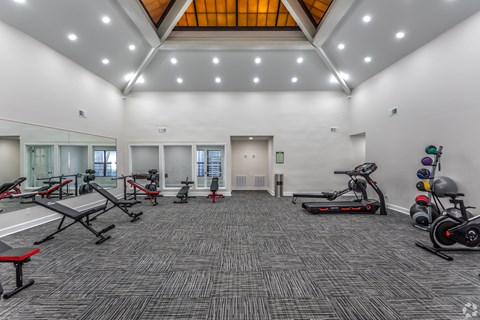 A spacious gym with a variety of equipment including treadmills, exercise bikes, and weight racks.