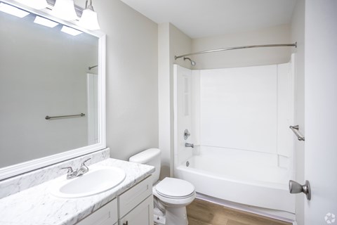 A white bathroom with a toilet, sink, and bathtub.
