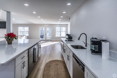 A kitchen with white cabinets and a wooden floor.
