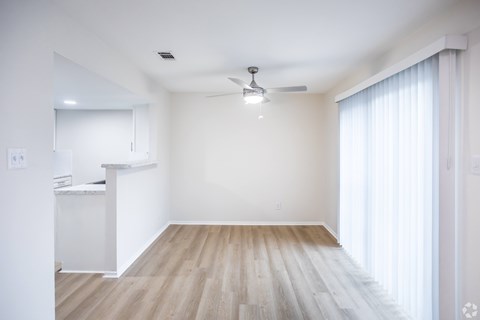 A room with a white ceiling, wooden floor, and a window with white curtains.