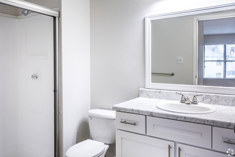 A white bathroom with a toilet, sink, and mirror.