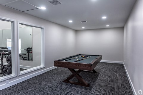 A room with a pool table and a mirrored wall.