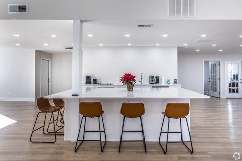 A kitchen with a white counter and bar stools.
