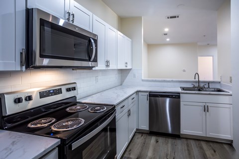 A modern kitchen with a stove top oven and microwave above it.