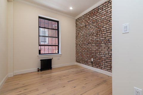 A room with a brick wall and a window with blinds.