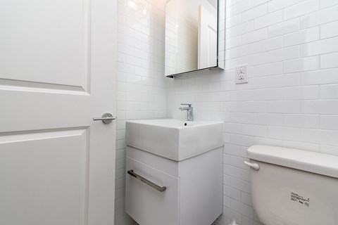 A white bathroom with a toilet, sink, and mirror.