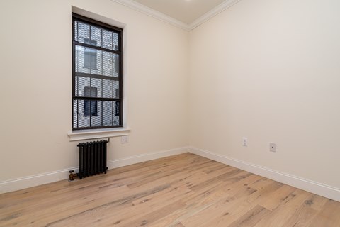 A room with a window and a radiator on the floor.