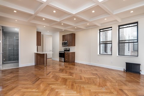 A spacious room with wooden flooring and a ceiling with recessed lighting.