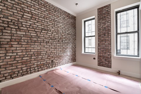 A room with a brick wall and two windows.