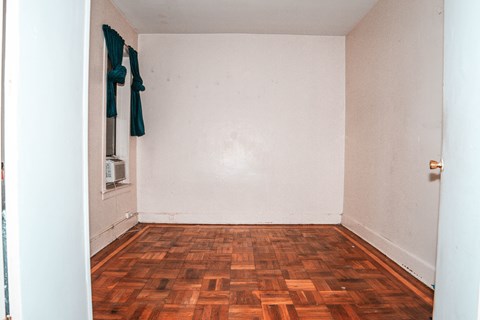 A room with a wooden floor and a white wall.