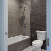 A white toilet sits next to a bathtub in a bathroom.
