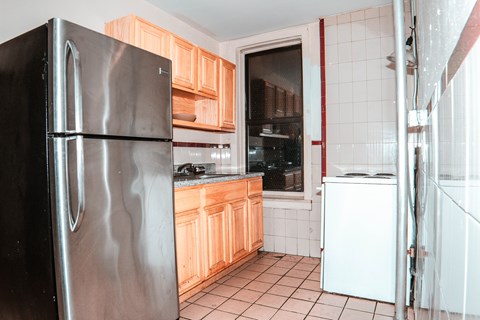 A kitchen with a black refrigerator and wooden cabinets.