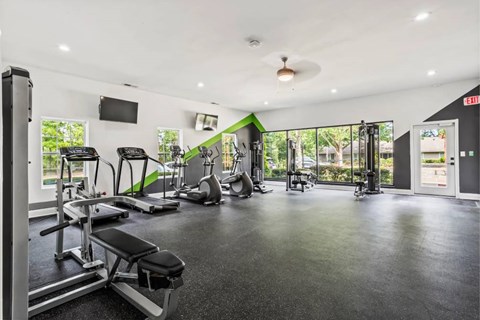 A gym with a variety of equipment including treadmills, weights, and exercise machines.