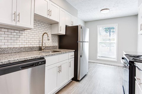 A kitchen with white cabinets and a black fridge.