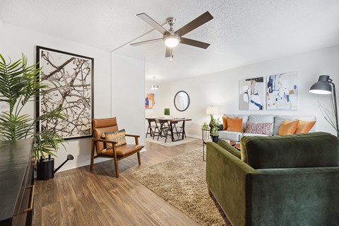 A living room with a green couch, a brown chair, and a wooden floor.