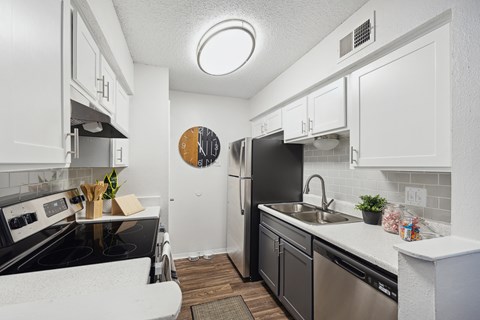 A kitchen with black appliances and white cabinets.