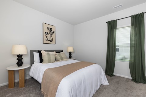 A bedroom with a bed, two lamps, and a picture on the wall.