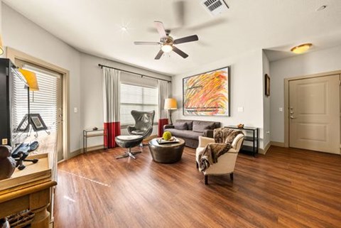A living room with a ceiling fan and a painting on the wall.
