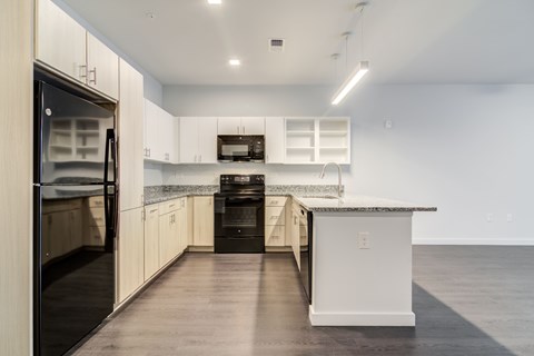 A modern kitchen with a black refrigerator and white cabinets.