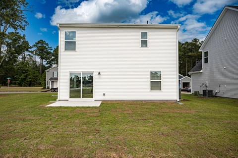 A white house with a glass door and a window is surrounded by a grassy area.