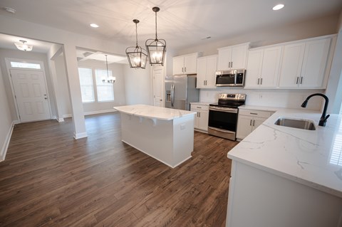 A kitchen with white cabinets and a wooden floor.