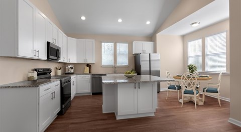 A modern kitchen with white cabinets and a wooden floor.