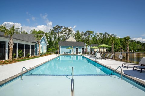 A large swimming pool with a diving board and a small building in the background.