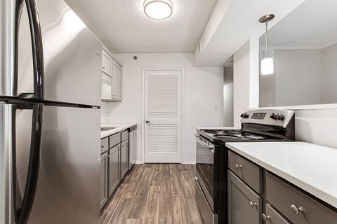 A kitchen with a stainless steel refrigerator and a stove top oven.
