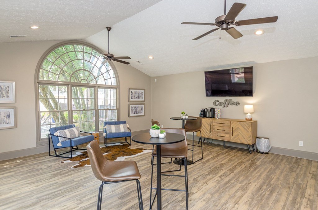 A living room with a ceiling fan, a couch, a chair, a table, and a television.