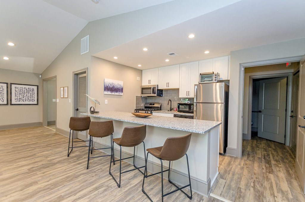 A kitchen with a white countertop and brown chairs.