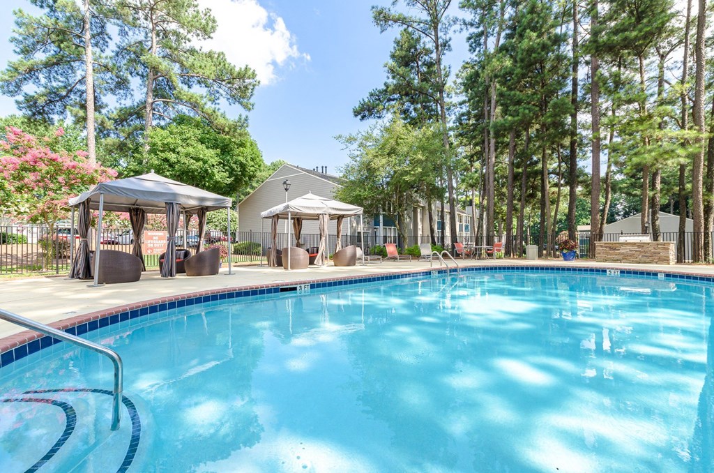 A large swimming pool surrounded by trees and pavilions.