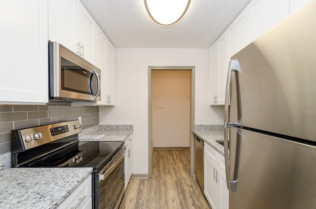 A kitchen with a stove, microwave, and refrigerator.
