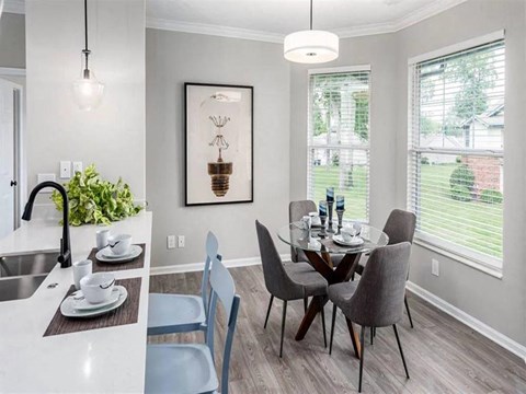 A dining room with a table set for two and a view of a backyard.