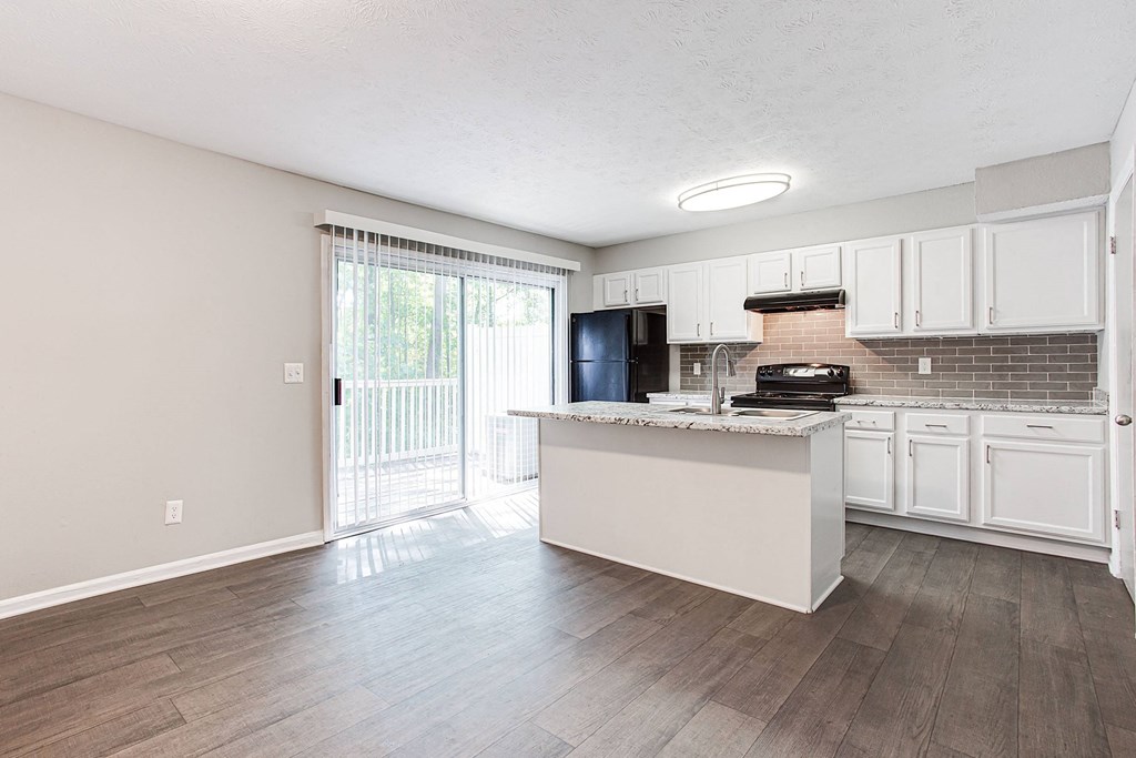 A kitchen with white cabinets and a black fridge.