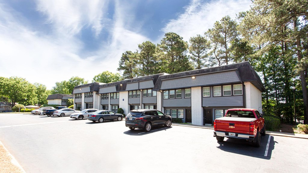 A parking lot with cars and a red truck in front of a building.