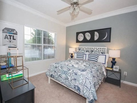 A bedroom with a bed, nightstand, and a ceiling fan.