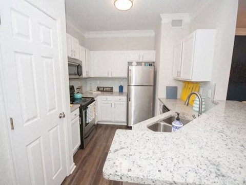 A kitchen with white cabinets and a granite counter.