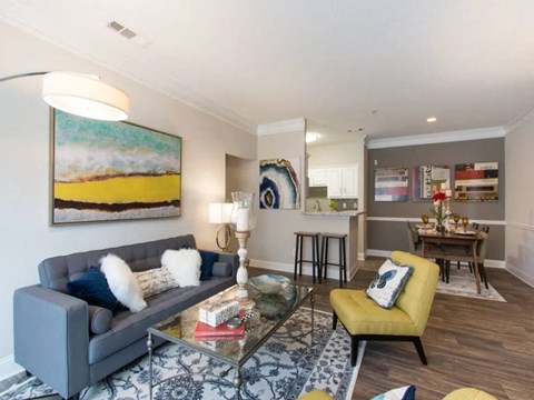 A living room with a grey couch, a yellow chair, and a painting on the wall.