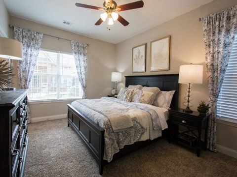 A bedroom with a bed, nightstand, and a ceiling fan.