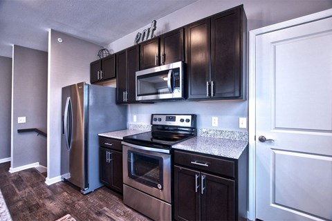 A kitchen with dark brown cabinets and stainless steel appliances.