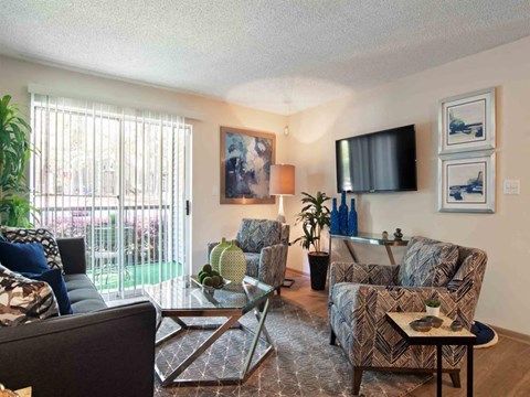 A living room with a couch, chairs, and a television.