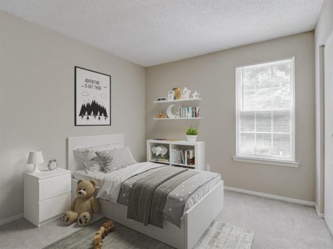 A bedroom with a poster on the wall that says "Adventure is out there" and a bed with a grey blanket.