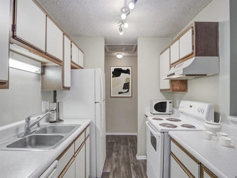 A kitchen with white appliances and wooden cabinets.